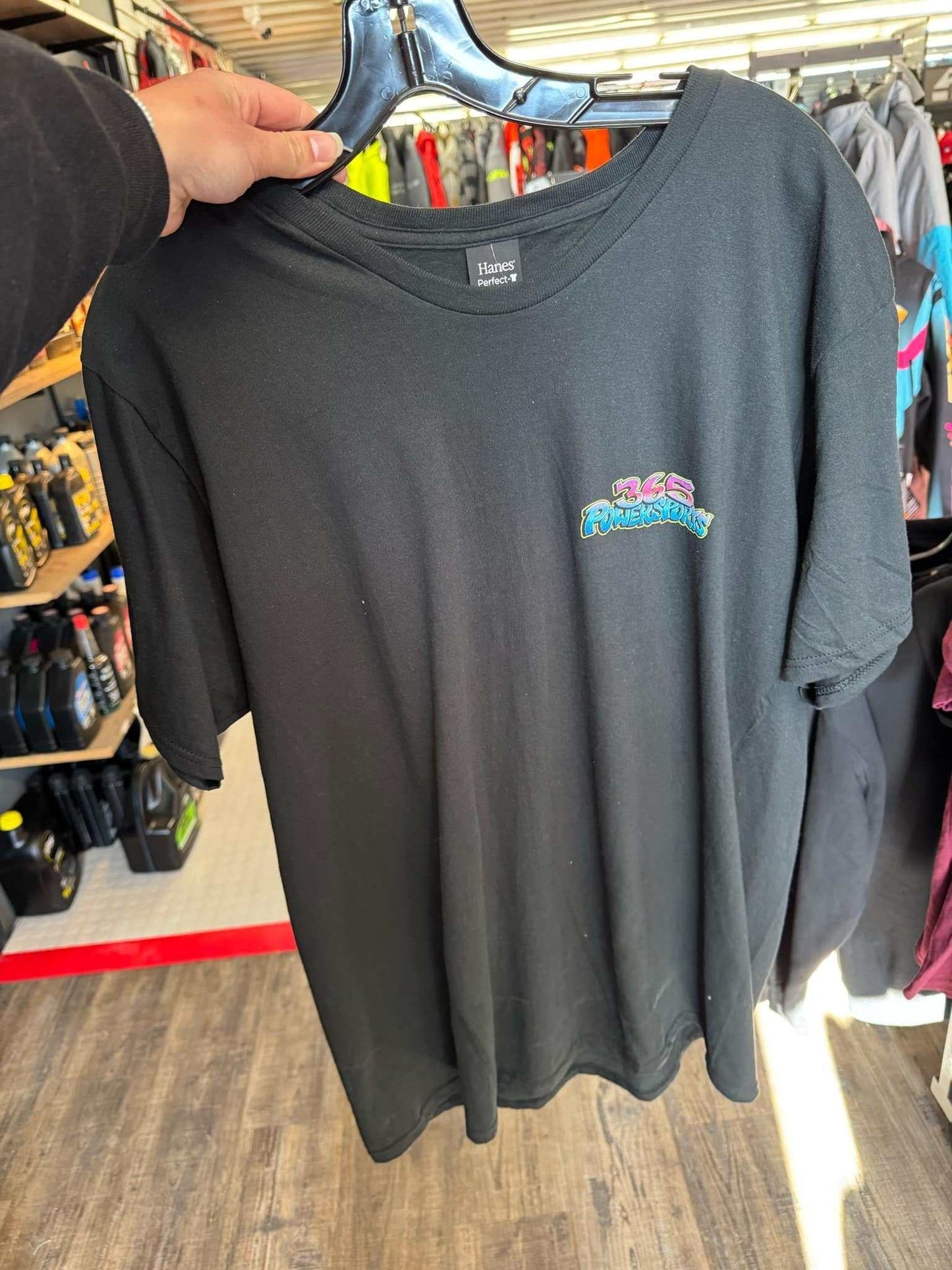 Black 365 Graffiti Tee displayed on hanger in store.