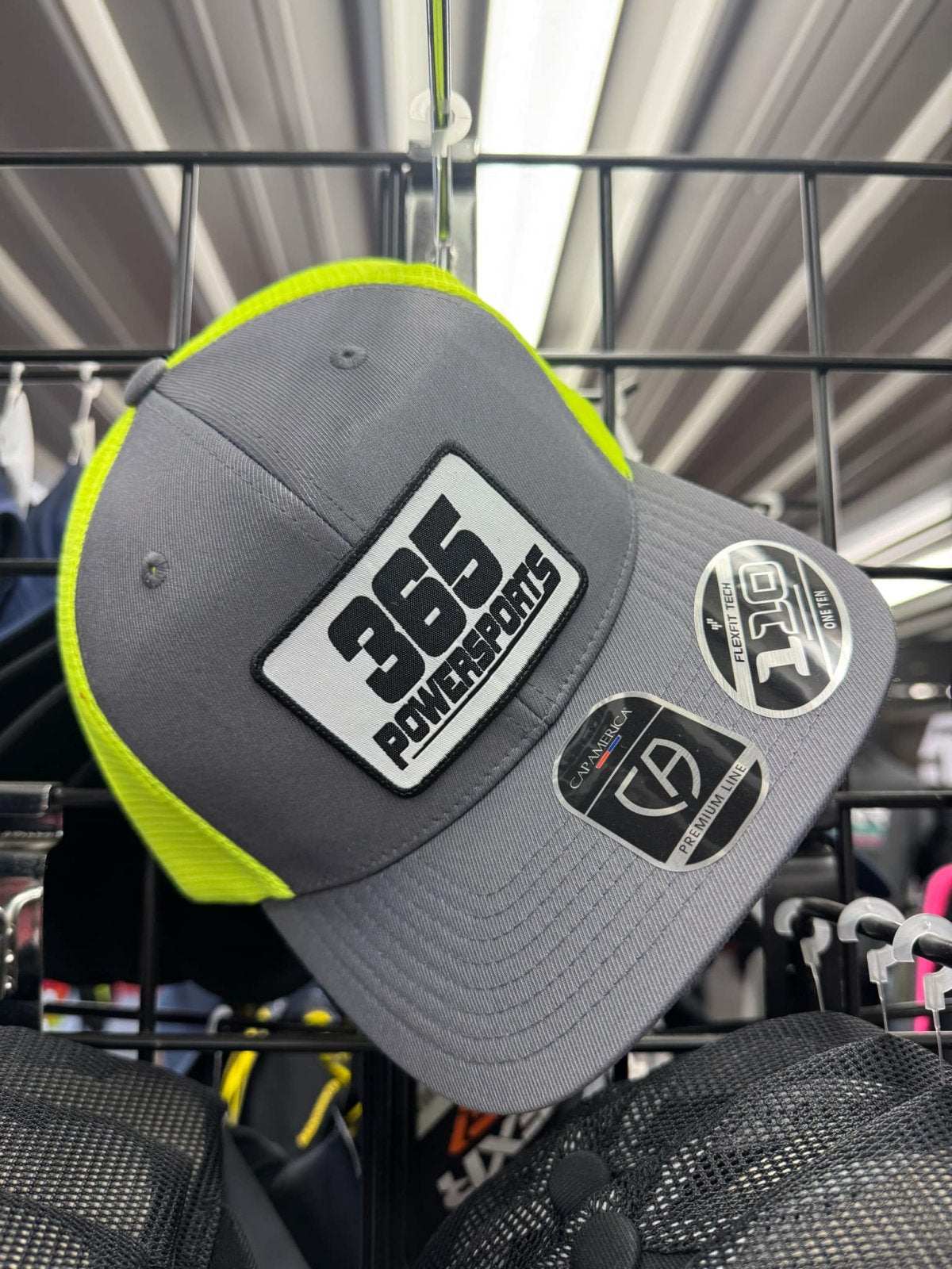 Gray 365 Flexfit 110 Woven Patch cap with neon yellow accents displayed on a rack.