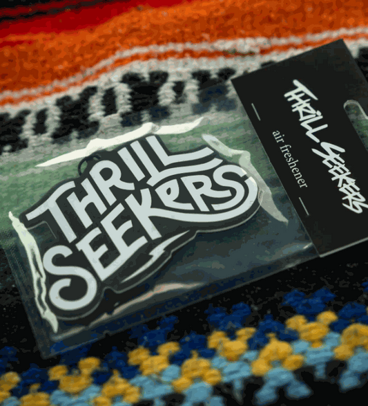 Thrill Seekers Paradise Air Freshener packaging on colorful fabric background.