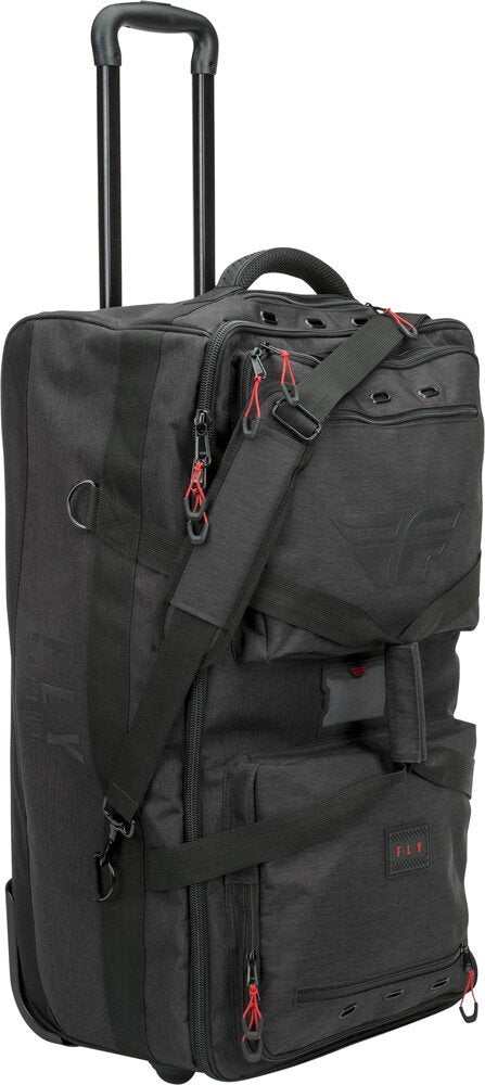 Black FLY Racing luggage tour roller bag with telescoping handle, shoulder strap, multiple zippered compartments, and vent grommets for gear ventilation.